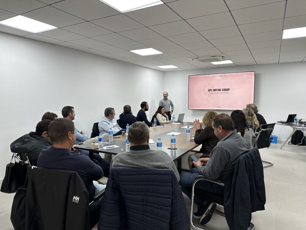 Asistentes a la reunion red dealers, alrededor de una mesa prestan atención al ponente.