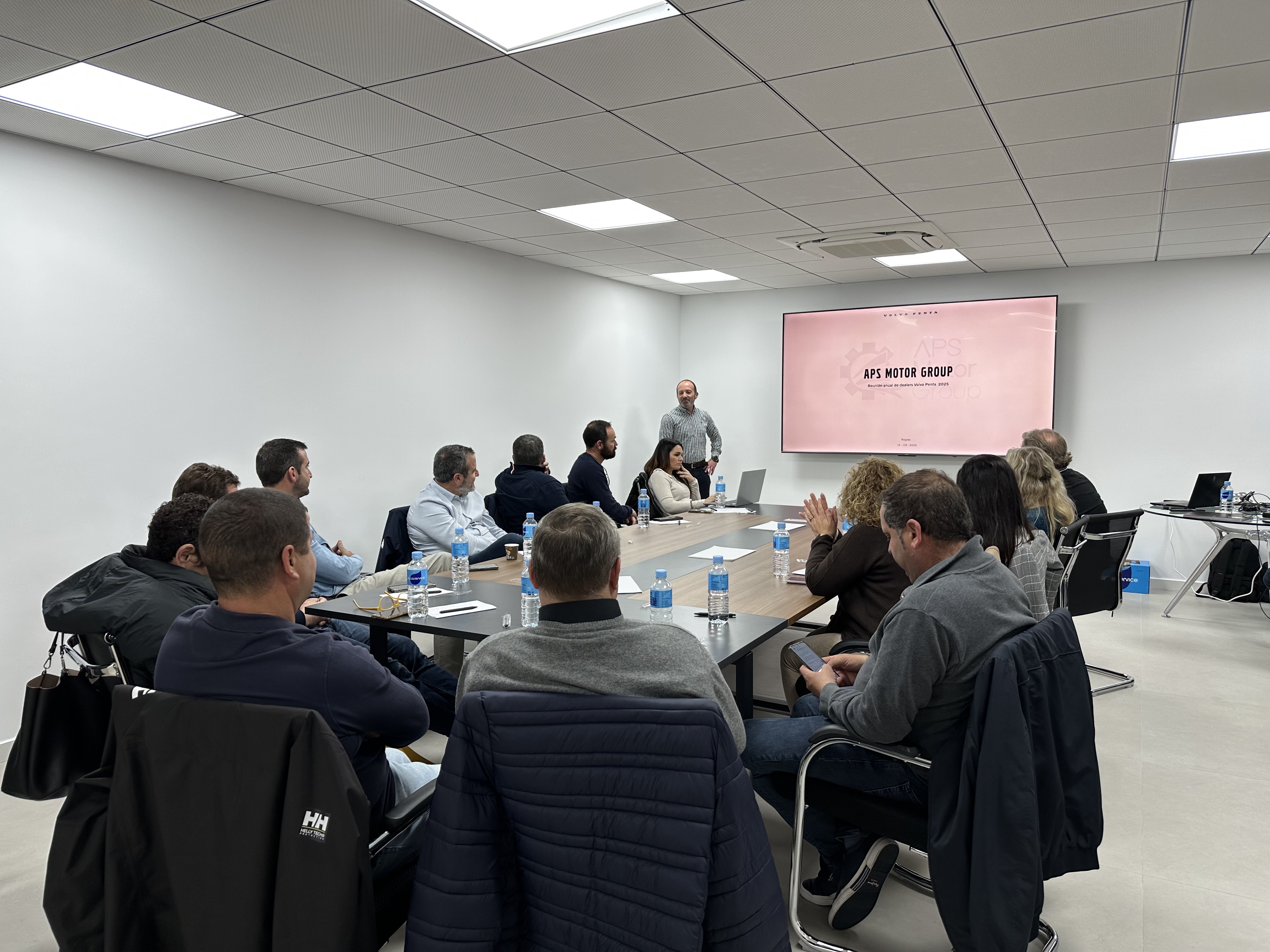 Asistentes a la reunion red dealers, alrededor de una mesa prestan atención al ponente.